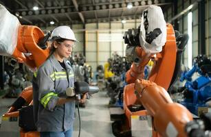 After installing a program on the robotic arm, a female engineer with a robotic arm controller performs a test run. photo