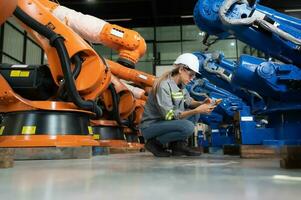 en el robots depósito, un hembra ingeniero inspecciona el eléctrico sistema de cada robótica brazo, antes de entregando a el cliente. foto