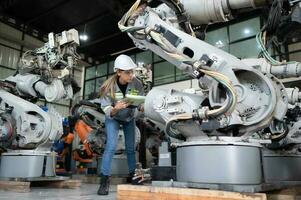 A female engineer checking documented items after installing a program on a robotic arm in a robotic warehouse and test the operation photo