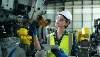A female engineer installs a program on a robotics arm in a robot warehouse. And test the operation before sending the machine to the customer. photo