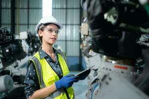 A female engineer installs a program on a robotics arm in a robot warehouse. And test the operation before sending the machine to the customer. photo
