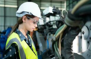 A female engineer installs a program on a robotics arm in a robot warehouse. And test the operation before sending the machine to the customer. photo