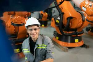 un hembra ingeniero instala un programa en un robótica brazo en un robot depósito. y prueba el operación antes de enviando el máquina a el cliente. foto