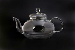 Empty transparent glass see through teapot kettle on black background photo