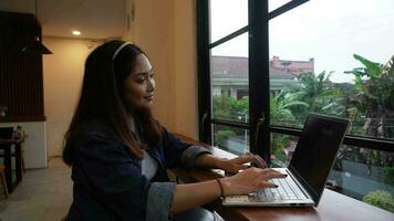 An adorable Asian woman is working with her laptop in a cafe video