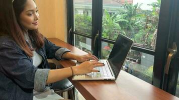 ein bezaubernd asiatisch Frau ist Arbeiten mit ihr Laptop im ein Cafe video
