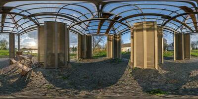 360 seamless hdri panorama view near wooden table next to benches inside modern gazebo near lake at evening in equirectangular spherical projection, ready AR VR virtual reality content photo