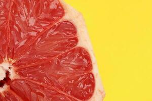 Ruby red grapefruit closeup macro pulp on yellow background photo