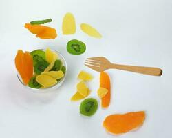 Dry preserved green kiwi pineapple ripe fruit slice colorful sweet on black marble slate background glass bowl flying floating elevated drooping photo