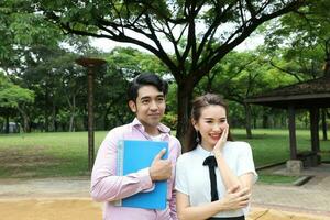 joven asiático malayo chino hombre mujer al aire libre parque caminar estar estudiar hablar discutir ordenador portátil archivo libro mochila actitud contento mezclarse Mira adelante foto