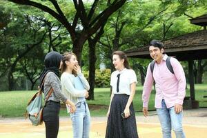 joven asiático malayo chino hombre mujer al aire libre parque libro archivo carpeta ordenador portátil computadora teléfono sentar estar estudiar mezclarse foto