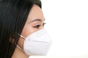 Beautiful young south east Asian woman wearing N95 anti virus bacterial surgical face mask on white background side view photo