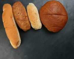 Freshly baked bread loaf bun roll round long mix verity copy text space border frame black background photo