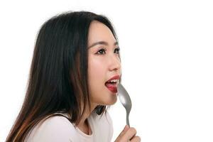 Beautiful young south east Asian woman pretend acting posing holding empty spoon in hand on lips tongue eat taste lick white background imagine yummy photo