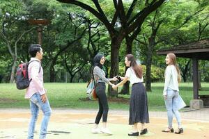 joven asiático malayo chino hombre mujer al aire libre parque libro archivo carpeta ordenador portátil computadora teléfono sentar estar estudiar mezclarse foto