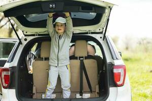 Boy inside car open trunk at picnic. photo