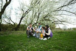 Family with three kids in spring meadow on the background of a flowering tree. photo