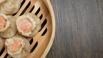 Prawn shrimp shaomai dim sum dumpling in bamboo steamer on rustic wood background photo