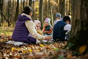 Mother with kids in family picnic at autumn forest. photo