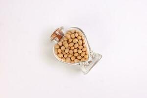 Soya beans in a hart shape glass bottle on white background photo