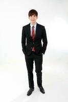 Young smart handsome Asian man business office wearing suit tie on white background walk forward photo