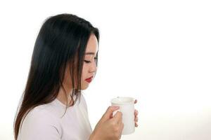 Beautiful young south east Asian woman holding white coffee tea cup emotion expression on white background look down photo