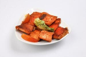 Pan friend salmon fish fillet in white triangular plate on white background photo