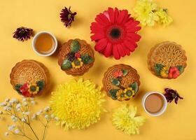 Colorful flower decorated moon cake Chinese mid autumn tea in small teacup festival daisy chrysanthemum mum rose baby breath flower red yellow pink purple violet on yellow background photo
