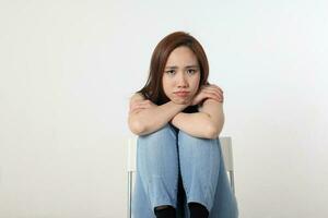 Young attractive Asian chinese malay woman pose face body expression mode emotion on white background think worry sitting legs up chin on keens photo