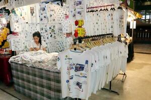 BANGKOK - June 15, 2018 t-shirt souvenir stall at night market in Pathum Wan district, ideal for artisan handicraft items. From cloths and watches to dry fruit and freshly cooked local delicacy. photo