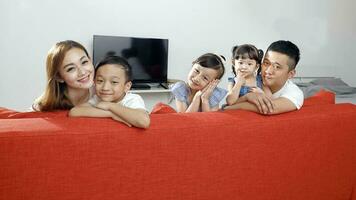 Parent mother father little child boy girl brother sister happy smile looking over the sofa photo