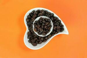 Coffee bean white ceramic cup hart shape plate bowl on orange color background photo