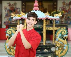 Young south east asian Chinese man woman traditional costume Chinese new year greeting outdoors at temple photo