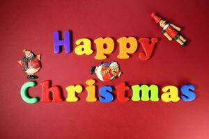 Happy Christmas sign on red paper background color plastic alphabet Santa clause nutcracker soldier ornament photo