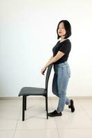 Young attractive south east asian woman pose face expression emotion on white background stand by chair photo