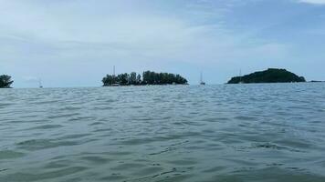 daylight wind small wave on ocean sea water near the beach at straits of Melaka small islands and boats floating photo