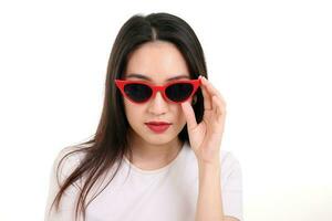 Beautiful young south east Asian woman wearing red frame dark sunglass pose fashion style white background photo