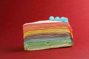 Rainbow crepe layer cake on red background photo