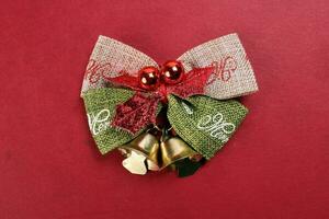 Small Christmas xmas gift bow ribbon Pine Arrangement bell on red background copy text space photo