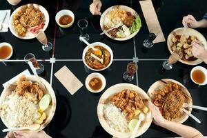 Young southeast asian woman group talk celebrate eating enjoying food rice curry noodle chicken drink cheers on dining table top view photo