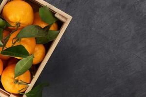 mandarin orange green leaf in wooden box crate top view copy text space on black slate marble background photo