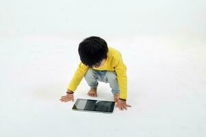 South East Asian young boy child playing tablet tab computer pc on white background photo