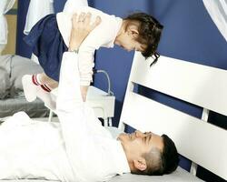 Parents father daughter playing happy laying on bed holding up photo