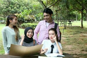 joven asiático malayo chino hombre mujer al aire libre parque libro archivo carpeta ordenador portátil computadora teléfono sentar estar estudiar mezclarse foto