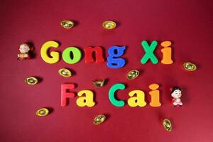 Plastic alphabet sign lettering Gong Xi Fa Cai Chinese New Year on maroon red paper background ornaments ingots photo