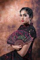 South east Asian Indian race ethnic origin woman wearing Chinese dress costume Cheongsam holding hand fan multiracial community on retro vintage background photo