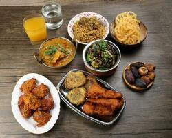 Bengali Iftar Ramadan breakfast spread ripe dates peep fried spicy piaju onion fitter eggplant tanpura potato chop haleem jilapi khichuri rice chana sola curry on rustic wooden table photo