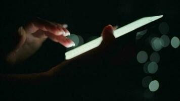 Woman is typing on a smartphone at night. Blurred lights in the background video