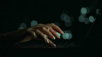 acelerado vídeo de hembra manos es mecanografía en un ordenador portátil a noche. borroso luces en el antecedentes. rápido movimiento video