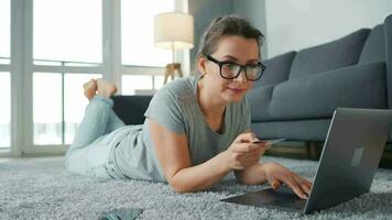 Woman with glasses is lying on the floor and working on a laptop. Concept of remote work video